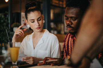 Diverse group of people collaborating and discussing in a meeting at a coffee bar, displaying teamwork and productivity.