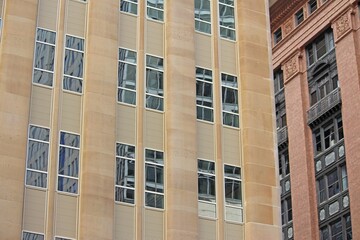 Cityscape of a rounded sandstone building in front of another historic building