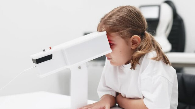 A girl participates in an engaging vision enhancement therapy using cutting-edge equipment. This laser treatment aids in restoring and developing visual skills.