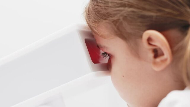 A girl participates in an engaging vision enhancement therapy using cutting-edge equipment. This laser treatment aids in restoring and developing visual skills.