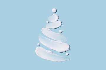 The concept of a Christmas tree in the form of cosmetic touches on a blue background. Moisturizing the skin in winter. Winter concept.