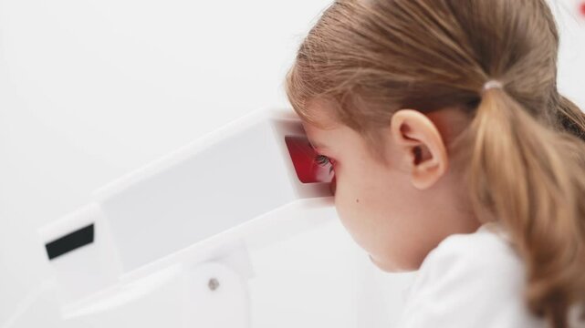 A girl participates in an engaging vision enhancement therapy using cutting-edge equipment. This laser treatment aids in restoring and developing visual skills.