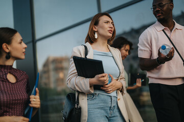 A diverse group of business people engaging in a discussion outside an office building, showcasing teamwork and collaboration in a business environment.