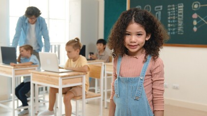 Caucasian energetic girl looking at camera while friend studying about writing engineering code or coding prompt. Skilled smart teacher checking prompt while teaching about AI generated. Pedagogy.