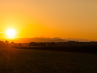 AERIAL, COPY SPACE: Scenic vista of a golden sunset gently illuminating the silhouettes of forest covered hills. Picturesque drone view of the vast countryside on a perfect autumn evening in Slovenia.