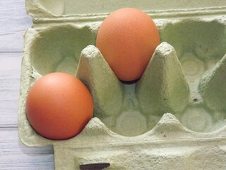  chicken eggs in an egg box on wooden background. High quality photo