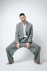 Fashion man model in grey suit, barefoot, shoot in studio