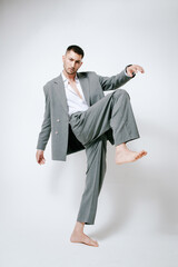 Fashion man model in grey suit, barefoot, shoot in studio