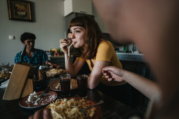 A group of friends gather around a table sharing a pasta meal in a warm and inviting atmosphere, highlighting friendship and togetherness.