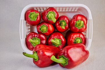 red sweet bell peppers lie in a white plastic rectangular basket tightly adjacent to each other, close-up, concept of ecology and naturalness