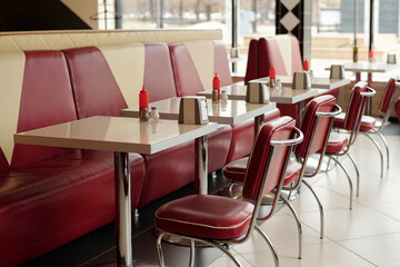 Interior of retro-style American diner with red leather booths and shiny dining tables, ketchup bottles, and classic diner decor creating nostalgic atmosphere