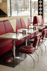 Classic retro diner setting featuring red booths and silver tables creating a nostalgic atmosphere with modern touches Expectedly quiet with empty tables and clean surfaces