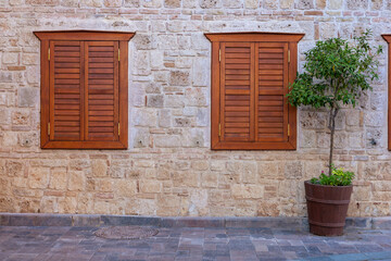 Rustic stone wall with wooden shutters and potted plant in a tranquil setting