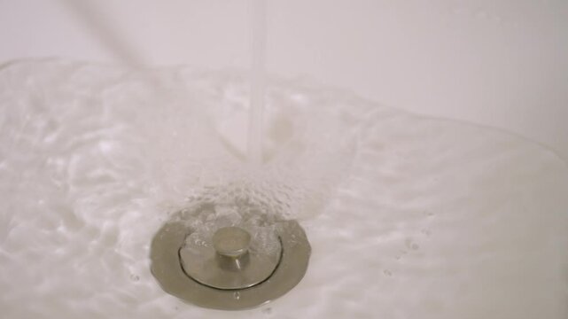 Sink with a closed stopper filling up with water. Close up.