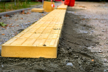 Road works. Laying pedestrian tiles with relief for the blind