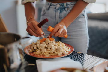 Close-up of a woman adding fresh vegetables to a pasta dish. The scene captures a casual cooking setting, emphasizing healthy eating and home-cooked meals.