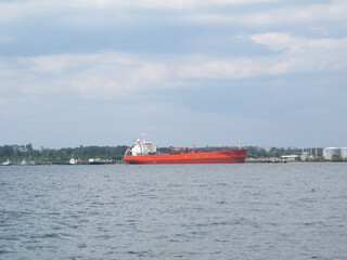 A large industrial cargo ship anchored in calm waters under a bright blue sky. The ship, with its...