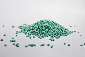 Mint green masterbatch granules on a white background, this polymer is a colorant for products in the plastics industry