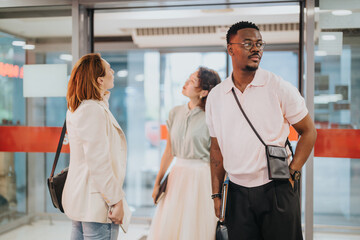 Obraz premium Three diverse individuals from a business team stand thoughtfully during a meeting outside. They appear engaged and focused, representing teamwork, diversity, and collaboration.