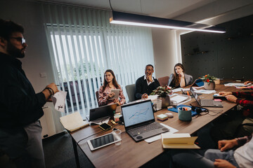 A focused team of business professionals are engaged in a meeting within a well-equipped office, analyzing growth charts while discussing strategic plans.