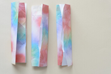 three colorful folded paper shapes with 3d element on blank paper