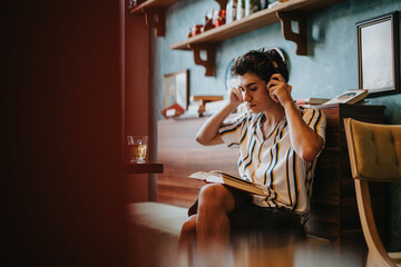 A young man wearing headphones, deeply immersed in reading a book, sits in a cozy room with warm lighting and a comforting ambiance.
