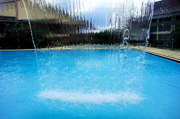 A fountain designed to resemble a waterfall, serving as a decorative feature for a family swimming pool