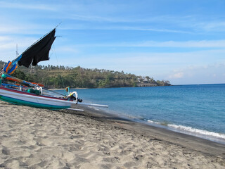 Coastal beach with a stretch of white sand on a cape, featuring a few anchored boats and a scenic view of a forest lining the shoreline