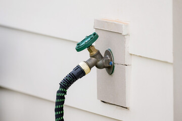 Outdoor water spout with green and black hose attached