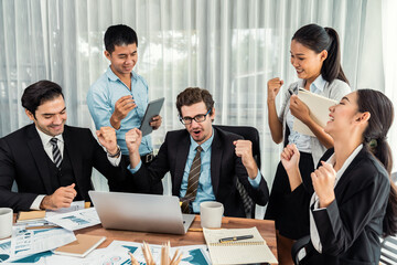 Group of happy businesspeople in celebratory gesture and successful efficient teamwork. Diverse race office worker celebrate after made progress on marketing planning in corporate office. Meticulous