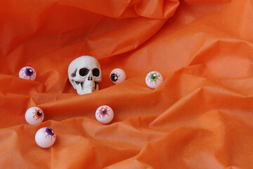 Halloween decoration featuring skull and eye balls on top of orange color fabric. Fantasy,...