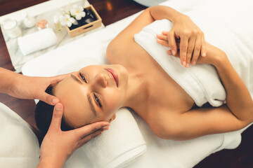 Caucasian woman enjoying relaxing anti-stress head massage and pampering facial beauty skin recreation leisure in dayspa modern light ambient at luxury resort or hotel spa salon. Quiescent