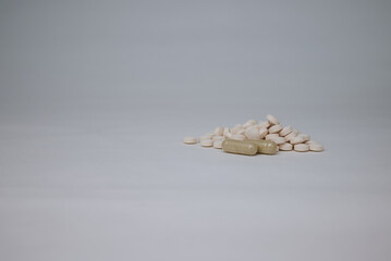 Pile of white tablets and capsules on plain background