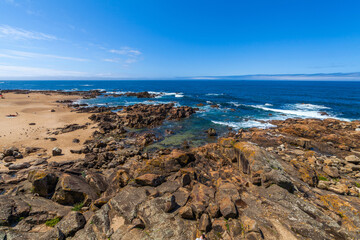 Waves crash against rocky outcrops in the blue ocean