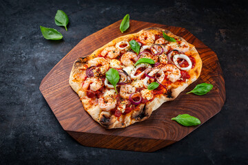 Traditional Italian pinsa bread prosciutto e salsa di pomodoro with seafood, buffalo mozzarella and tomato sauce served as close-up on a wooden design tray