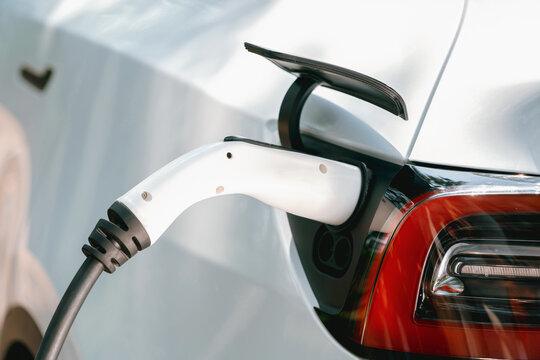Closeup EV plug charger attached to EV car for battery recharging from electric charging station using clean and sustainable energy. Natural protection and eco friendly car travel concept. Exalt