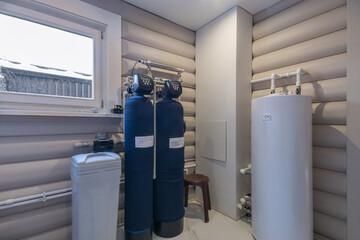 Gas boiler room in a private wooden house. Blue cylinders with sensors, a white water .tank.