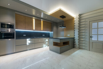 The interior of a modern kitchen in a wooden house made of light logs. Light grey .kitchen set with built-in appliances.