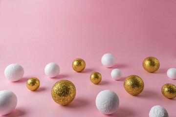 Gold and white glitter ball decoration on pink background with copy space. New Year minimal concept.