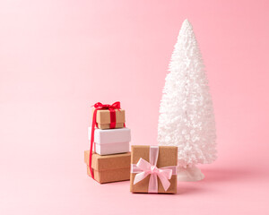 Snowy Christmas tree with gift boxes on pastel pink background. Christmas or New Year minimal concept.