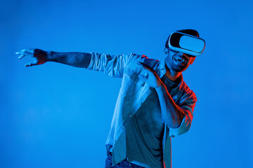 Handsome smart man dancing and moving gesture to music by using VR glasses with neon light...