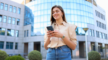 Beautiful, young businesswoman enjoying in the city and using smartphone