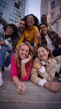 Vertical. Camera zoom in and out of group young funny urban people enjoy together. Gen z friends looking happy posing excited fooling around sharing good moments outdoors. Friendship and community