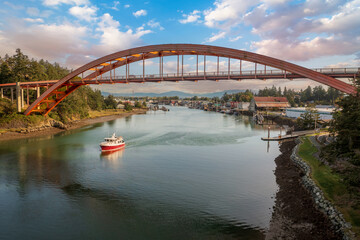 Naklejka premium Historic Rainbow Bridge in the tourist town of La Conner, Washington with a boat passing underneath. The bridge connects the town to the island that is part of the Swinomish Indian Reservation. 