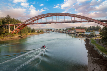 Historic Rainbow Bridge in the tourist town of La Conner, Washington with a boat passing underneath. The bridge connects the town to the island that is part of the Swinomish Indian Reservation. 