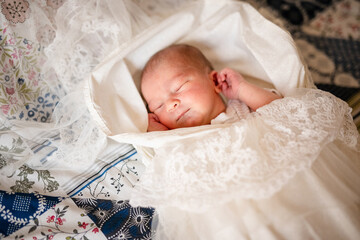 Newborn baby for the first time at home, lying in a blanket on the bed, smiling, yawning, pulling pens, falling asleep, baby's morning, baby products concept.