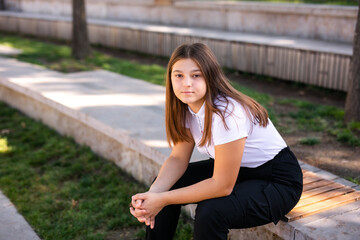 A 16-year-old girl in a school uniform sits on the steps of the street