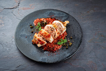 Fried calamari tubes stuffed with rice in salsiccia mince tomato sauce served as close-up on a...