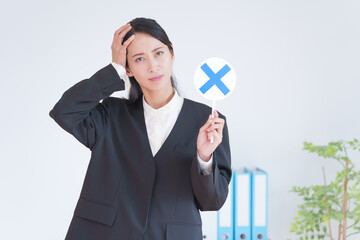 マルバツの札を持つ働くビジネス女性