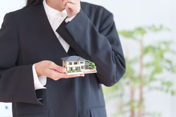 家の模型を持つ不動産営業マン女性